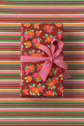 Rollo de papel de regalo Amalfi: regalo envuelto con la cara A (flores) y cinta rosada sobre papel de la cara B (franjas)